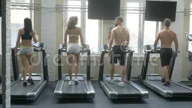 健身女孩和男人在健身房跑步机上跑步。 年轻健康的人在跑步机上跑步。 健身和健康的生活方式